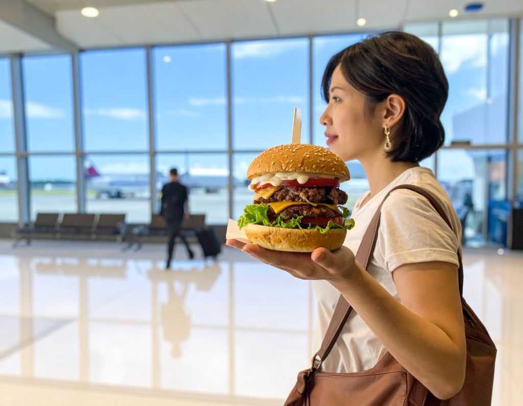 Travelers enjoying Shake Shack burgers at an airport.