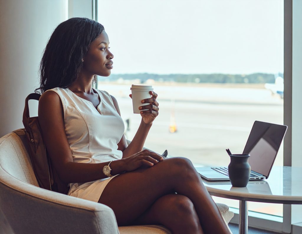 Traveller relaxing in a modern airport lounge with coffee and laptop.