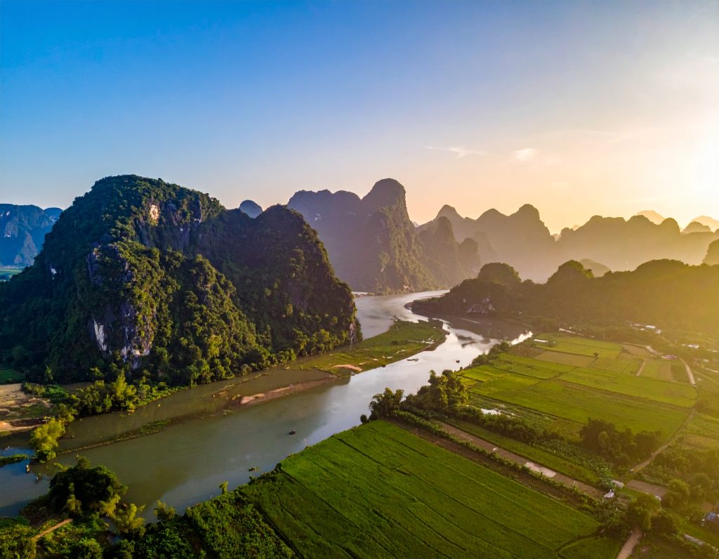 Limestone cliffs and blue lagoon in Vang Vieng, Laos, with travellers kayaking.