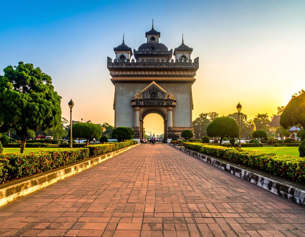 Golden That Luang stupa with skyline view of Vientiane, Laos.