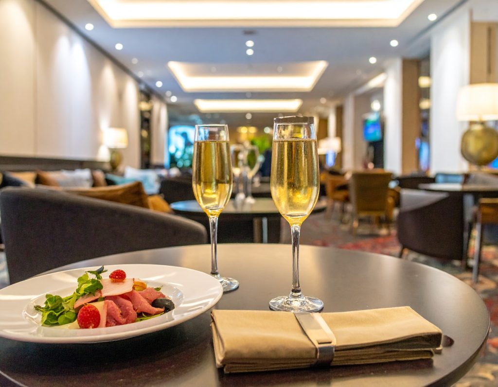 Luxurious Lounge Singapore Airlines, buffet area, travellers enjoying wine and snacks.